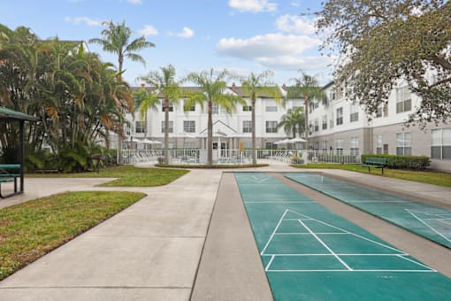 a tennis court is in front of a building with palm trees