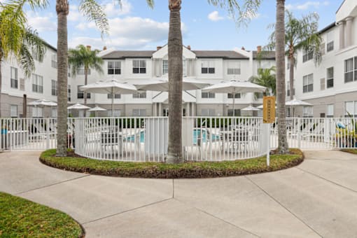 an apartment building with a white fence and palm trees