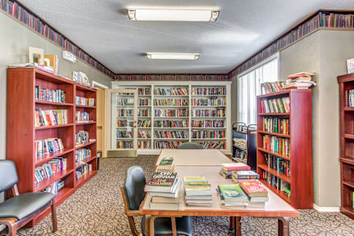 a library with a table and bookshelves full of books