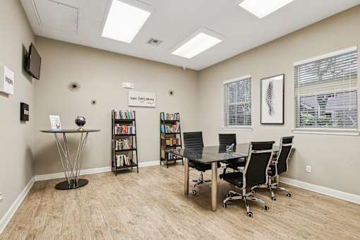 A room with a table, chairs, and bookshelves.