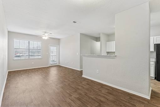 A spacious living room with hardwood floors and white walls.