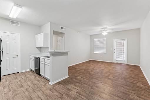 A kitchen with white cabinets and a wooden floor.