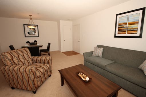 Living room with carpet flooring, couch, coffee table, chair, and dining room table with pendant lighting
