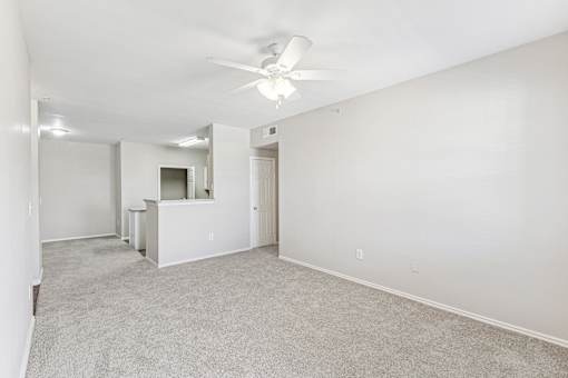 A spacious room with a ceiling fan and carpeted floor.
