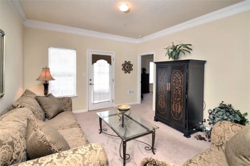 Livingroom with tan carpet, beige walls, and ceilings. Furniture throughout the room with the patio door in the background.