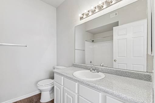 A white bathroom with a toilet, sink, and mirror.