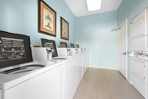 a laundry room with white washers and dryers and blue walls