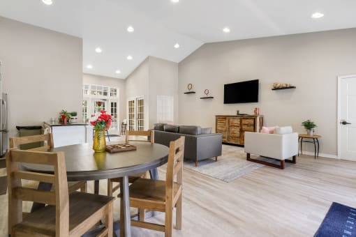 a living room and dining room with a table and chairs and a tv on the wall