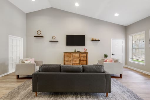 office lounge area with a couch and chairs and a tv on the wall