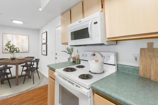 a kitchen with green countertops and a white stove top oven with a white microwave above it
