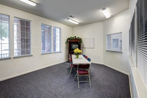 Resident Lounge Room with Large Windows Folding Table and Chairs in Front of a TV in an Entertainment Center
