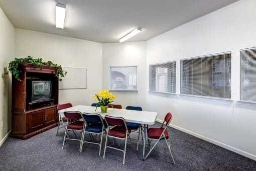 Resident Lounge Room with Large Windows Folding Table and Chairs in Front of a TV in an Entertainment Center