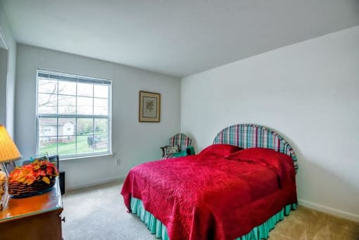 Model Bedroom with a Large Window and Colorful Bed Wood Dresser