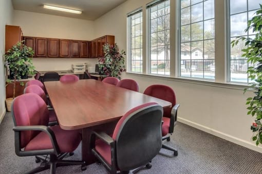 Conference Room with Large Table and Rolling Chairs Decorative Trees and Large Windows