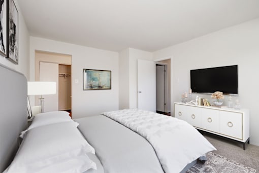 staged bedroom with a bed and a dresser with a television on top of it