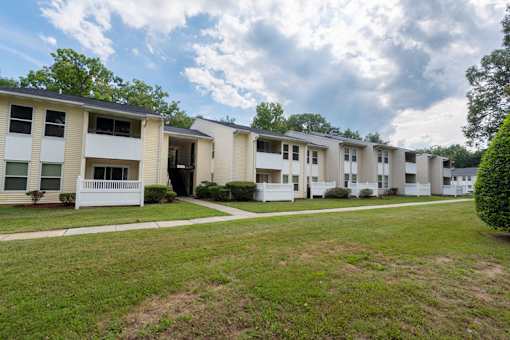 a row of apartment buildings with grass and trees