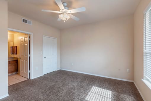 a bedroom with a ceiling fan and a door to a bathroom