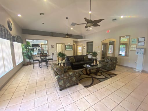 Interior of the clubhouse with ceramic tile flooring, couches, coffee table, and ceiling fans.