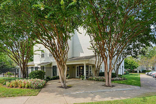 A white house with a grey roof is surrounded by trees.