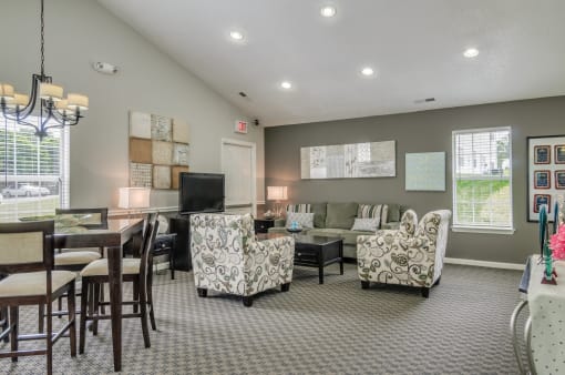 Clubhouse with sofa, coffee table, arm chairs. High top table with chairs. Television on an entertainment center.
