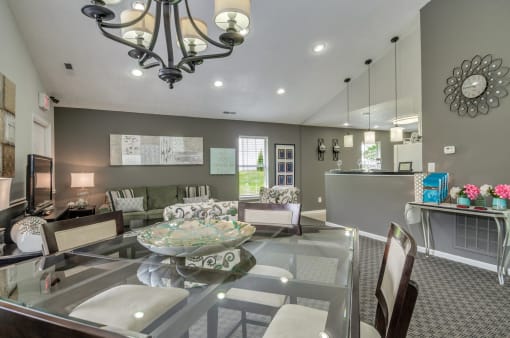 Clubhouse with glass dinner table with chairs. Sofa and arm chairs in the background.