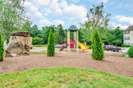 Playground with tress and parking lot in the background.