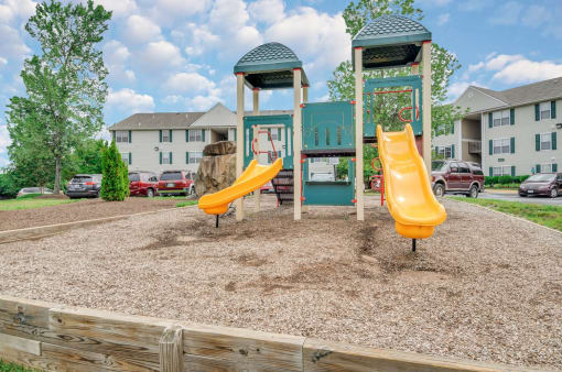 Playground with wood chips in court yard between buildings.