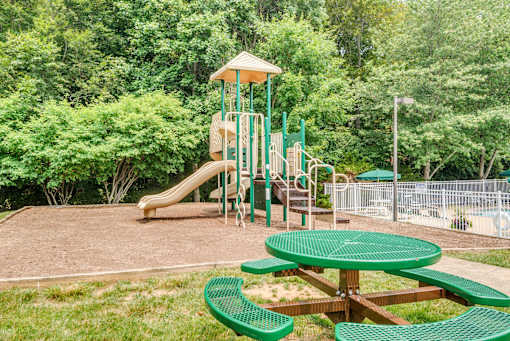 A playground with a green slide and a yellow canopy.