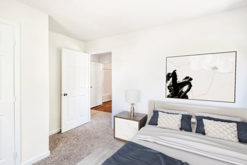Virtually staged; Carpeted Bedroom with Closet adn Open Doorway Showing Hallway to Bathroom with bed and night stand and grey/blue accent colors