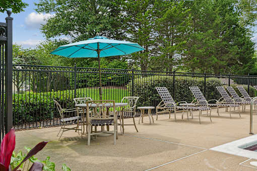 A patio with a table and chairs and a blue umbrella.