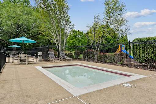A small pool surrounded by a black fence and trees.