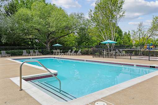 A swimming pool surrounded by trees and a fence.
