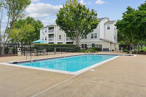 A swimming pool in front of a white apartment building.