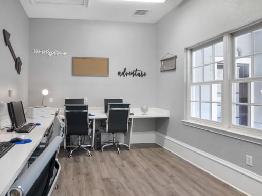 Business center with four desktop computers with flat-screen monitors, four chairs,