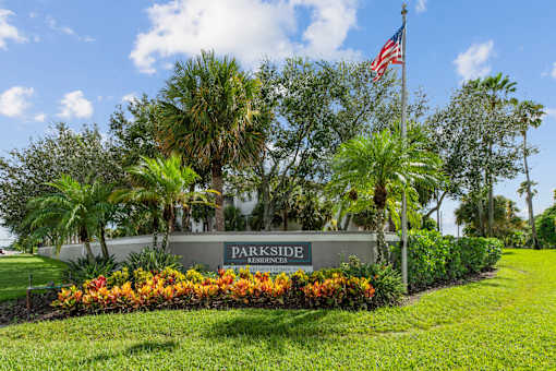 A sign that says Parkside Residences in front of some trees.