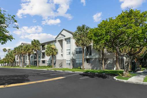 A street view of a residential area with apartment buildings and palm trees.