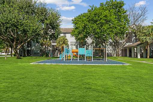 A playground with a blue swing set and a green lawn.