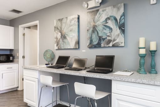 an office with three laptops on a counter with chairs