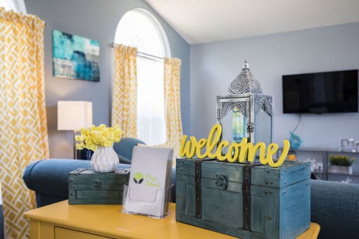 a yellow and blue living room with crates and a welcome sign