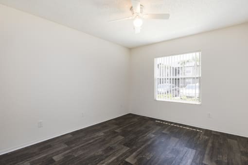 an empty living room with a window and wood flooring