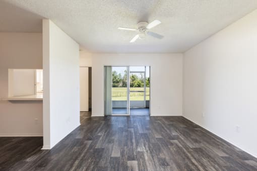 an empty living room with a ceiling fan and a sliding glass door