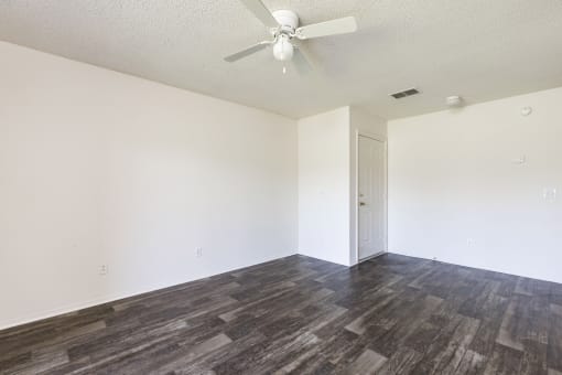 an empty living room with white walls and a ceiling fan