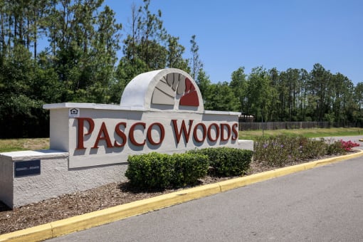 a sign for pasco woods at the side of a road
