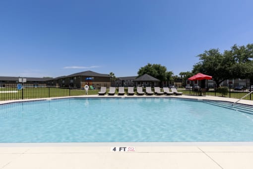 a swimming pool with white lounge chairs and a building in the background