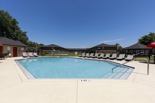 a resort style pool with chairs around it and buildings in the background