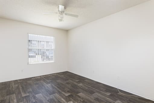 an empty living room with a window and wood flooring