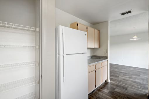 an empty kitchen with a white refrigerator and cabinets