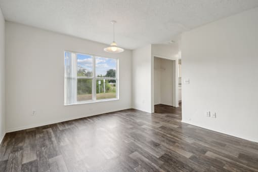 an empty living room with a large window and wood flooring