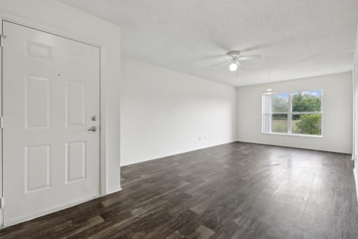 an empty living room with a ceiling fan and a window