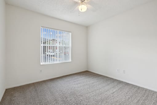 an empty room with a window and a ceiling fan